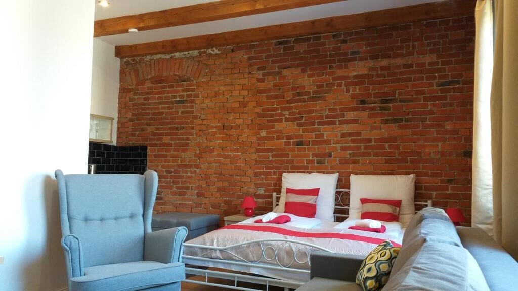 Apartament z ceglaną ścianą, łóżkiem i fotelem